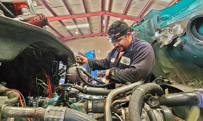 A technician examining electrical wires in semi-truck