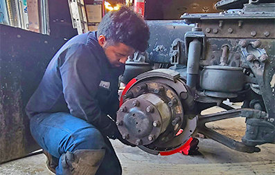 Mechanic conducting maintenance on semi-truck suspension system.